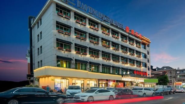 Un hotel de varios pisos con un letrero llamativo que dice "HAO TING HOLIDAY HOTEL".
