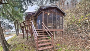 Une cabane en bois dotée d’une structure vitrée et d’un escalier menant à une terrasse.