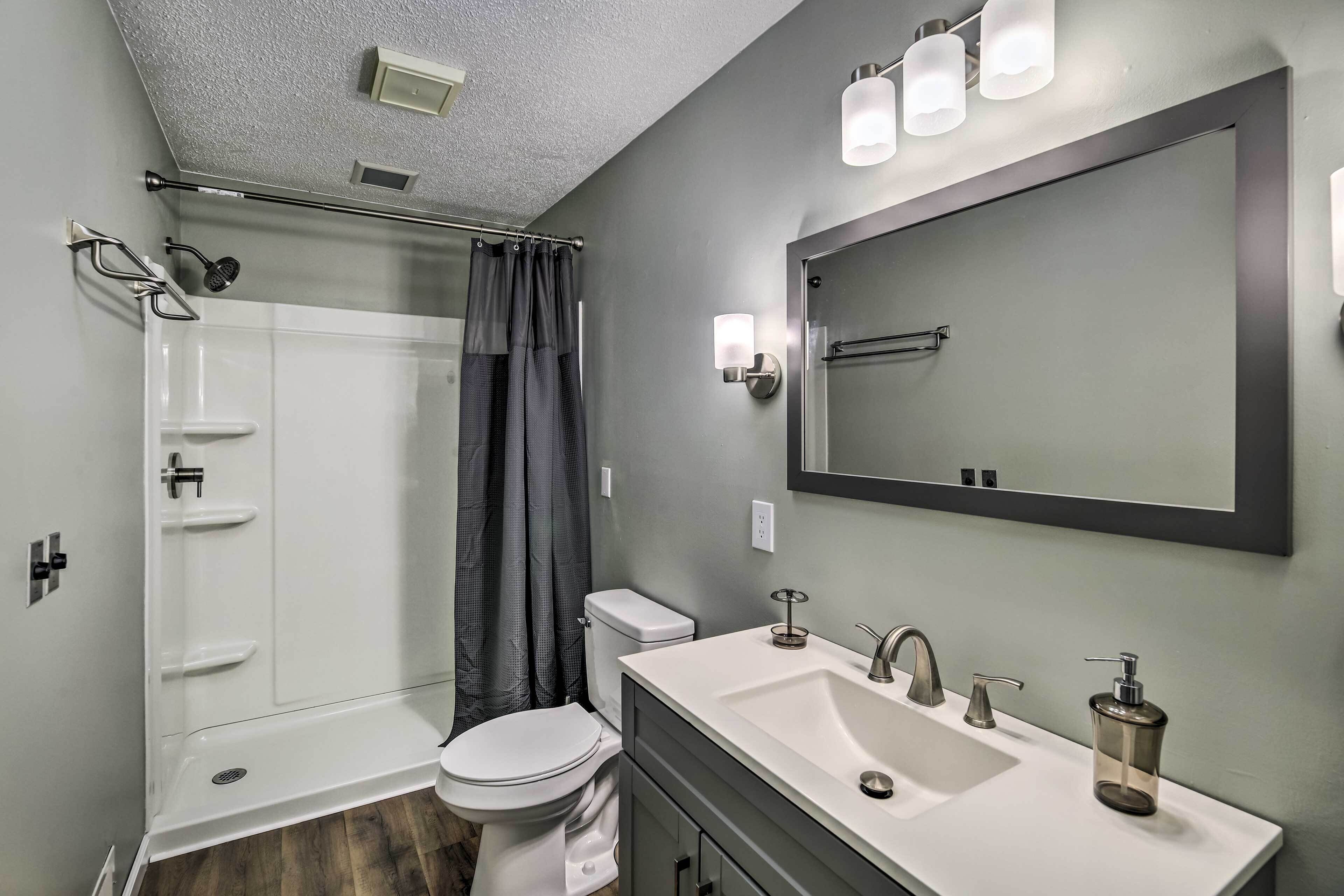 A modern bathroom with a glass shower enclosure, a toilet, a sink with a mirror, and a shower curtain.