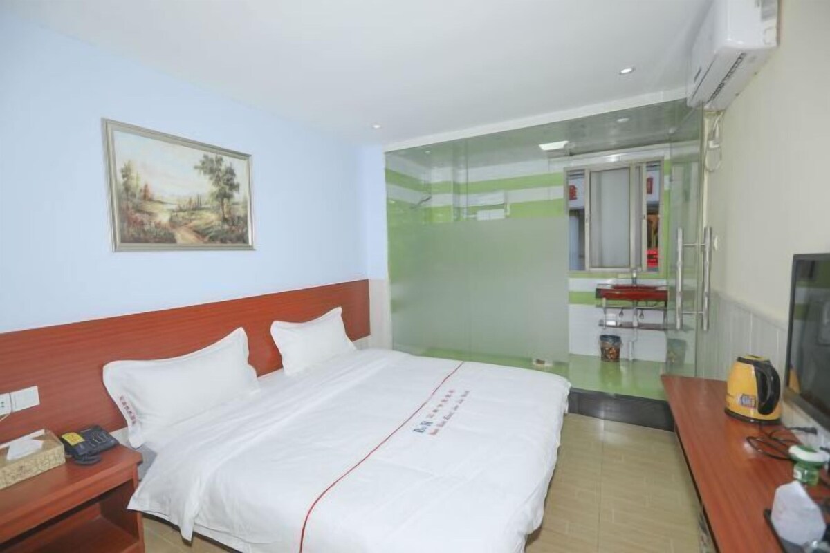 Habitación de hotel con cama, mesita de noche y televisor.