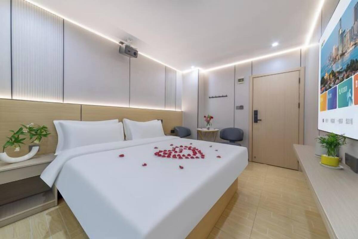 A hotel room with a bed, bedside table, and a small desk with a chair.