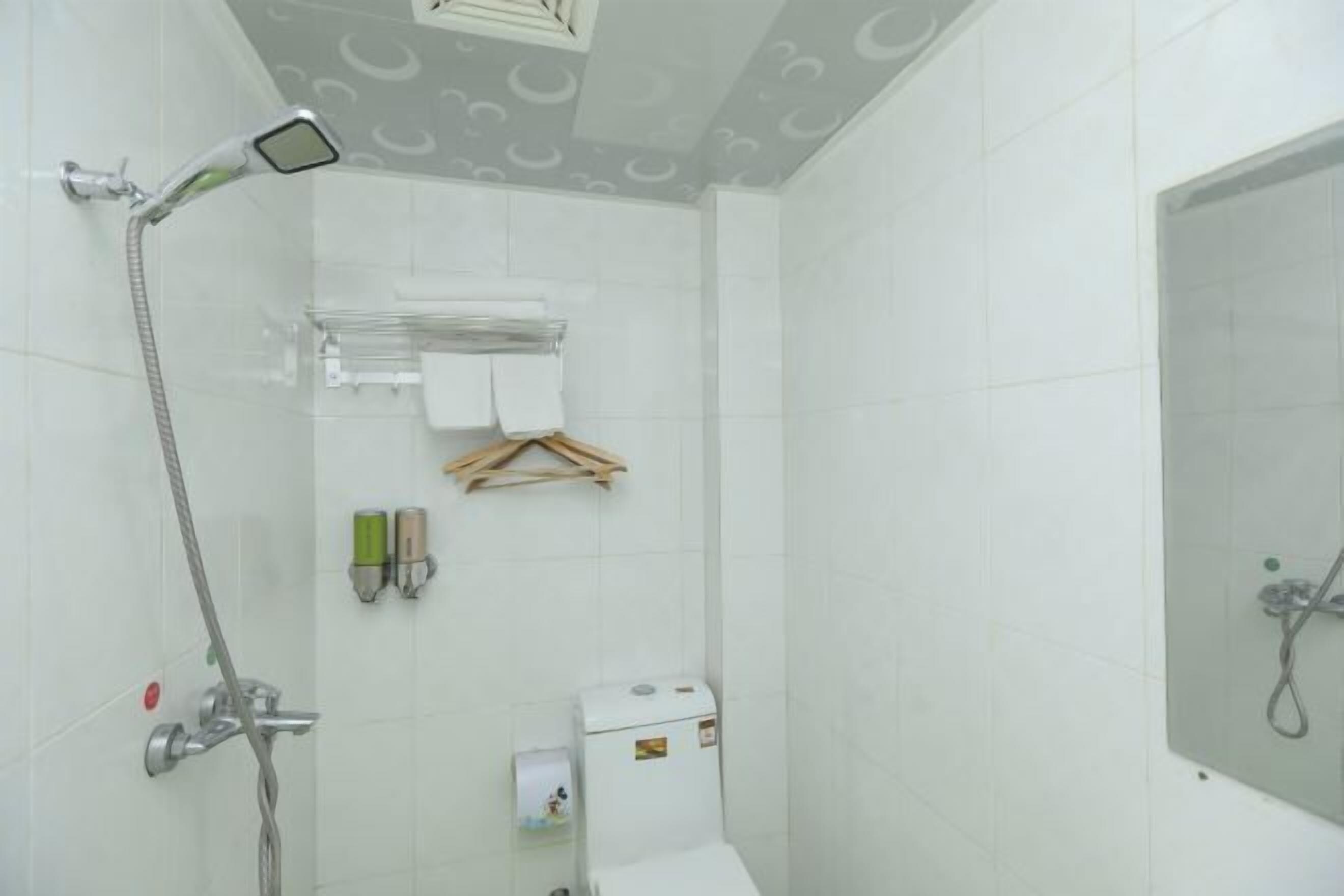 Un baño pequeño y blanco con ducha, inodoro y toallero.