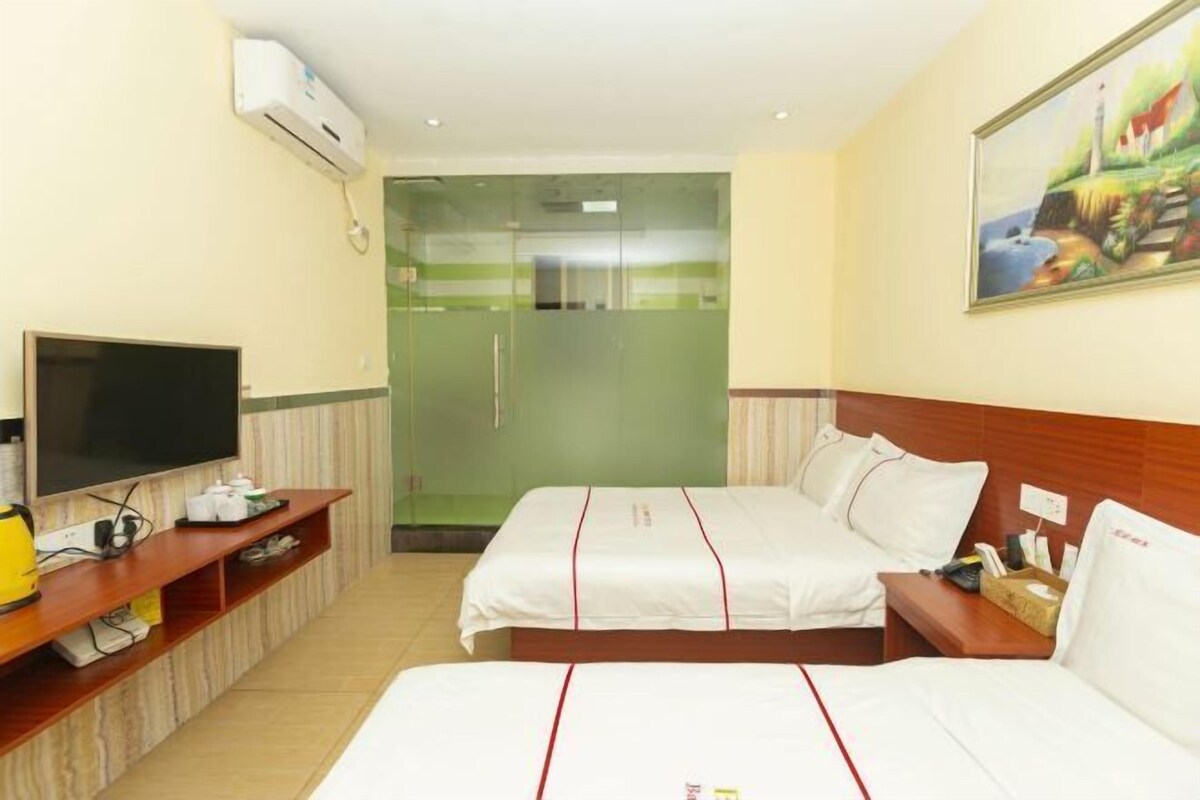 Una habitación de hotel con dos camas, televisión, cafetera y un cuadro en la pared.