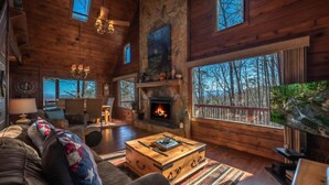 A spacious living room with a fireplace, large windows, and a cozy seating area.