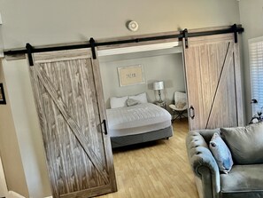 A bedroom with a bed, a chair, a bedside table, and a sliding door. - 1/2 a block  from cherry creek north shops (Denver)