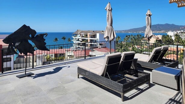 A rooftop terrace with lounge chairs and umbrellas, overlooking a coastal cityscape and the ocean. - Casa de Elena – Tranquility, Peace & Relaxation (Bucerias)