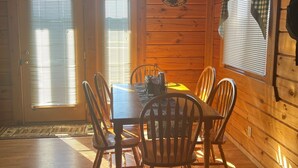A wooden cabin interior with a dining table and chairs, a hanging light fixture, and a window with blinds. - Cozy 3 Bed 2 Bath Cabin located next to Three Bears Resort in Warrens Wisconsin  (Warrens)