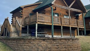 A log cabin with a balcony and a stone foundation. - Cozy 3 Bed 2 Bath Cabin located next to Three Bears Resort in Warrens Wisconsin  (Warrens)