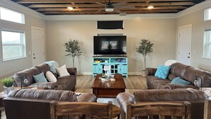 A living room with two brown leather sofas, a wooden coffee table, and a flat-screen TV mounted on the wall. - Hill Country Lodge * Great for Groups & Multi Family Gatherings (Doss)