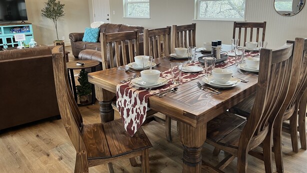 A dining area with a wooden table set for four, surrounded by wooden chairs. - Hill Country Lodge * Great for Groups & Multi Family Gatherings (Doss)