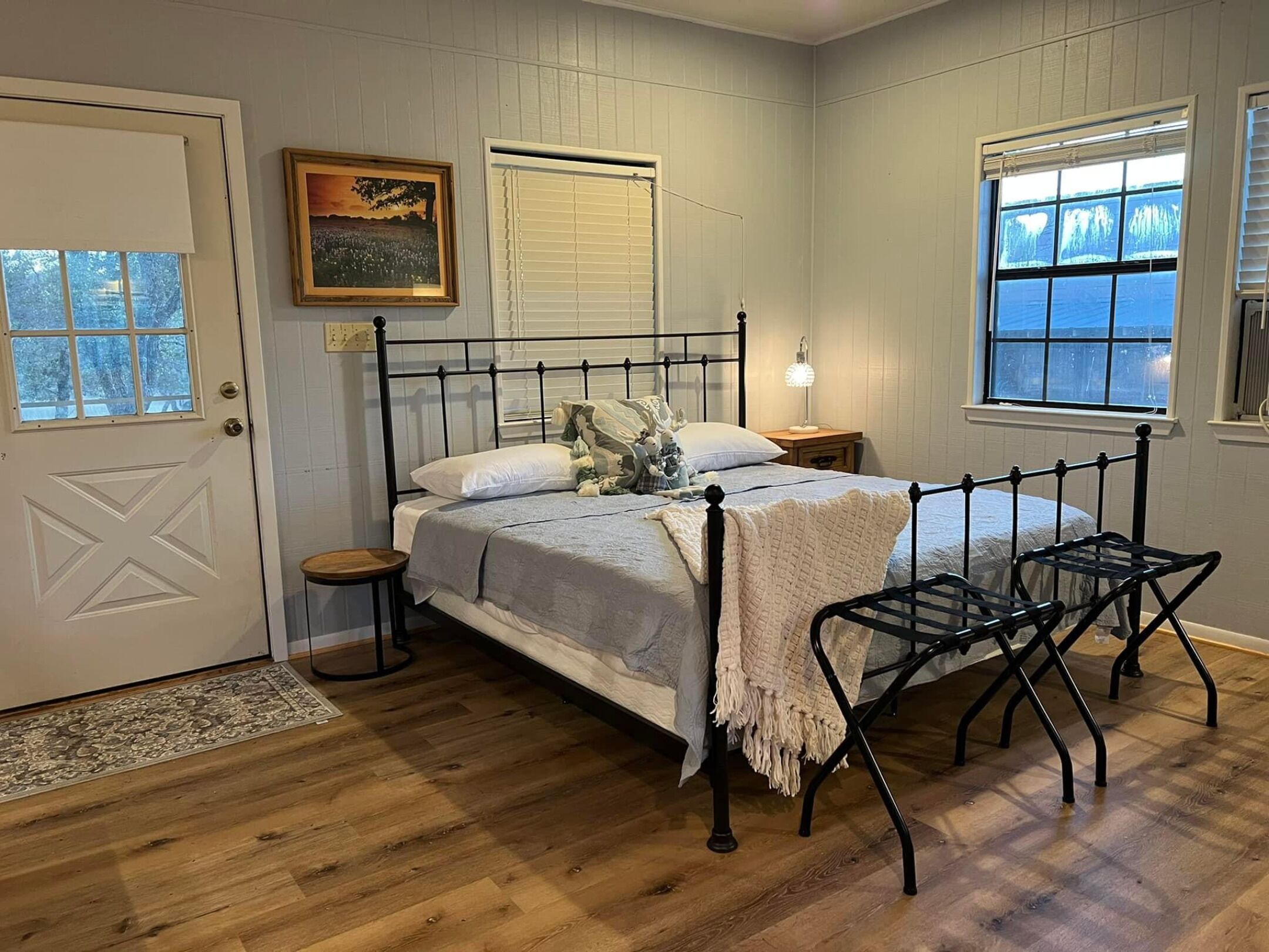 A bedroom with a bed, bedside tables, a window, and a door.