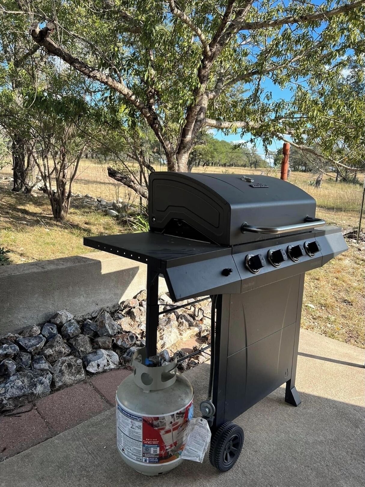 Una parrilla portátil con tanque de gas, ruedas y panel de control.