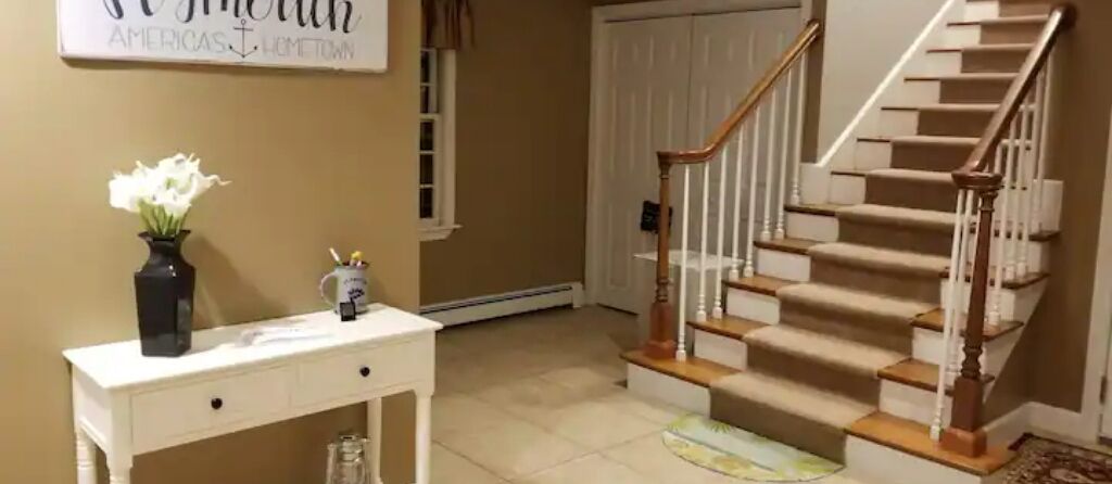 A staircase with wooden steps and white railings, leading to a door.