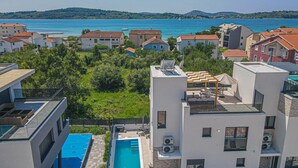 Zona residencial con edificios modernos, piscina y vista al mar.