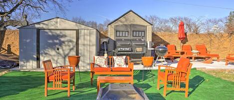 A backyard with a barbecue area, outdoor furniture, and a shed.