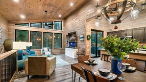 A spacious cabin interior with a dining area, kitchen, and living room. - Perfect Modern Cabin for Couples Hot Tub Indoor Fireplace Pet friendly (Sevierville)