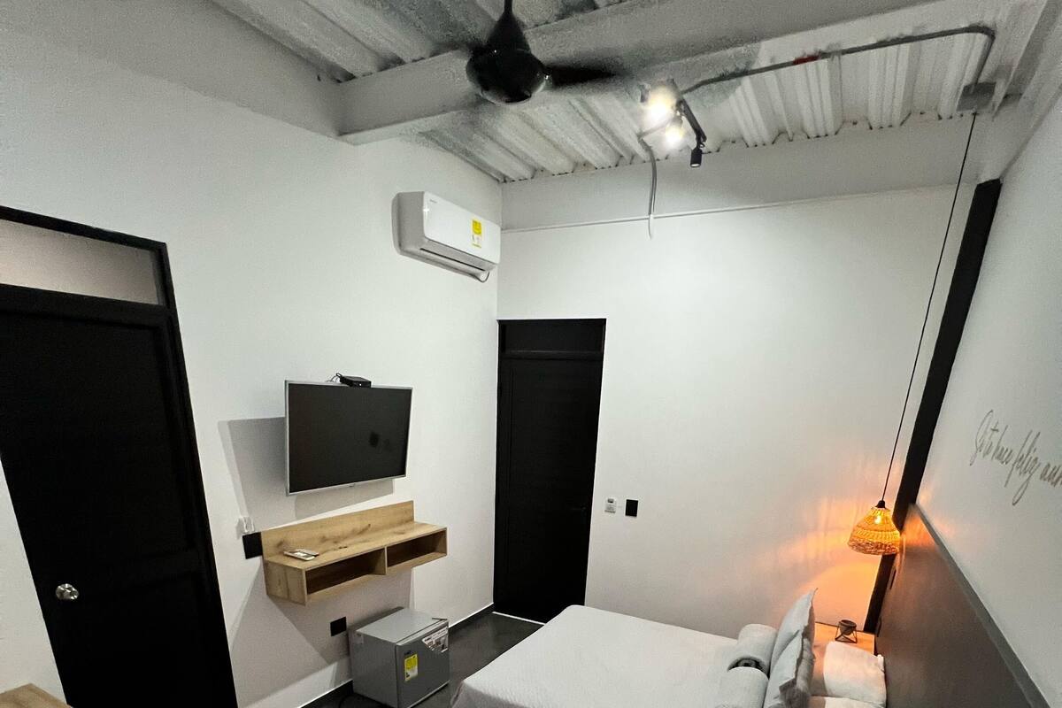 Een moderne hotelkamer met twee bedden, een flatscreen-tv, een bureau met een computer en een wandairconditioner.