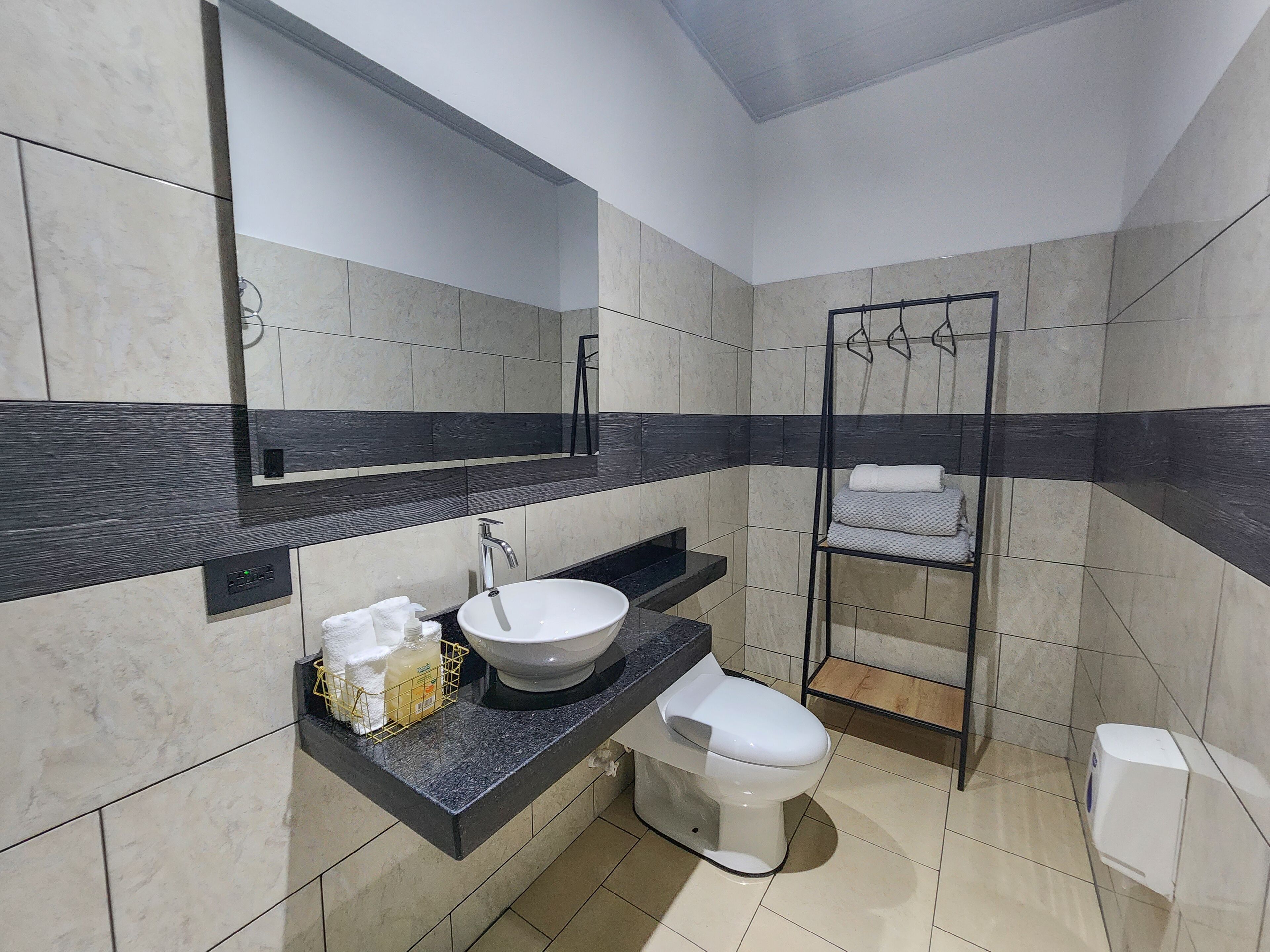 Un baño moderno con un espejo grande, un lavabo, un inodoro y una ducha.