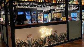 A bar area with shelves of liquor bottles, a refrigerated display, and a neon sign.