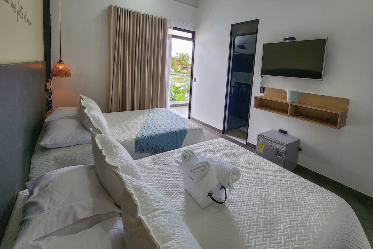 Een hotelkamer met twee bedden, een televisie, een minibar en uitzicht op de omgeving.