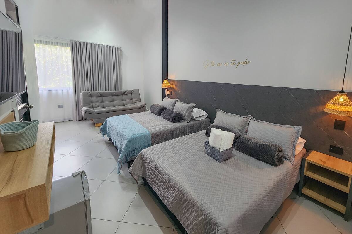 Een moderne hotelkamer met een bed, twee nachtkastjes, een bank en een bureau.