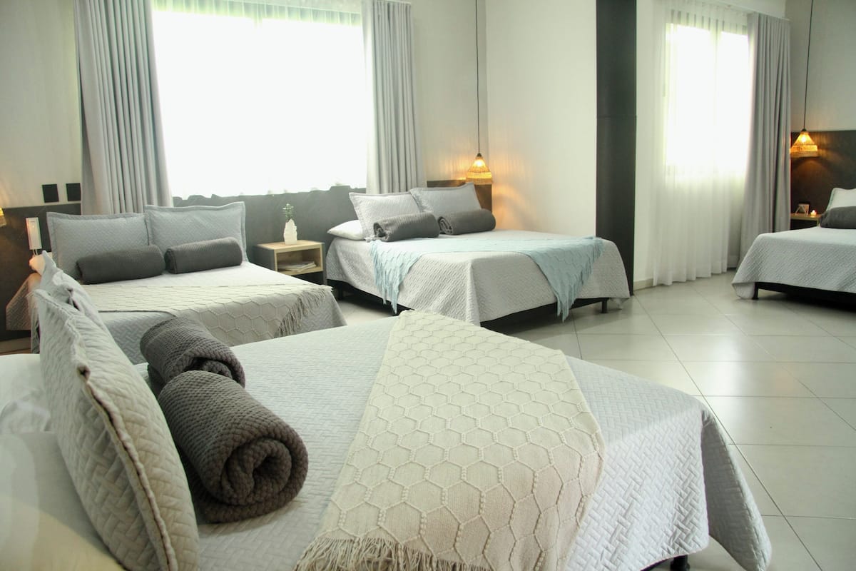 Een hotelkamer met twee bedden, een nachtkastje, een lamp en een raam met gordijnen.