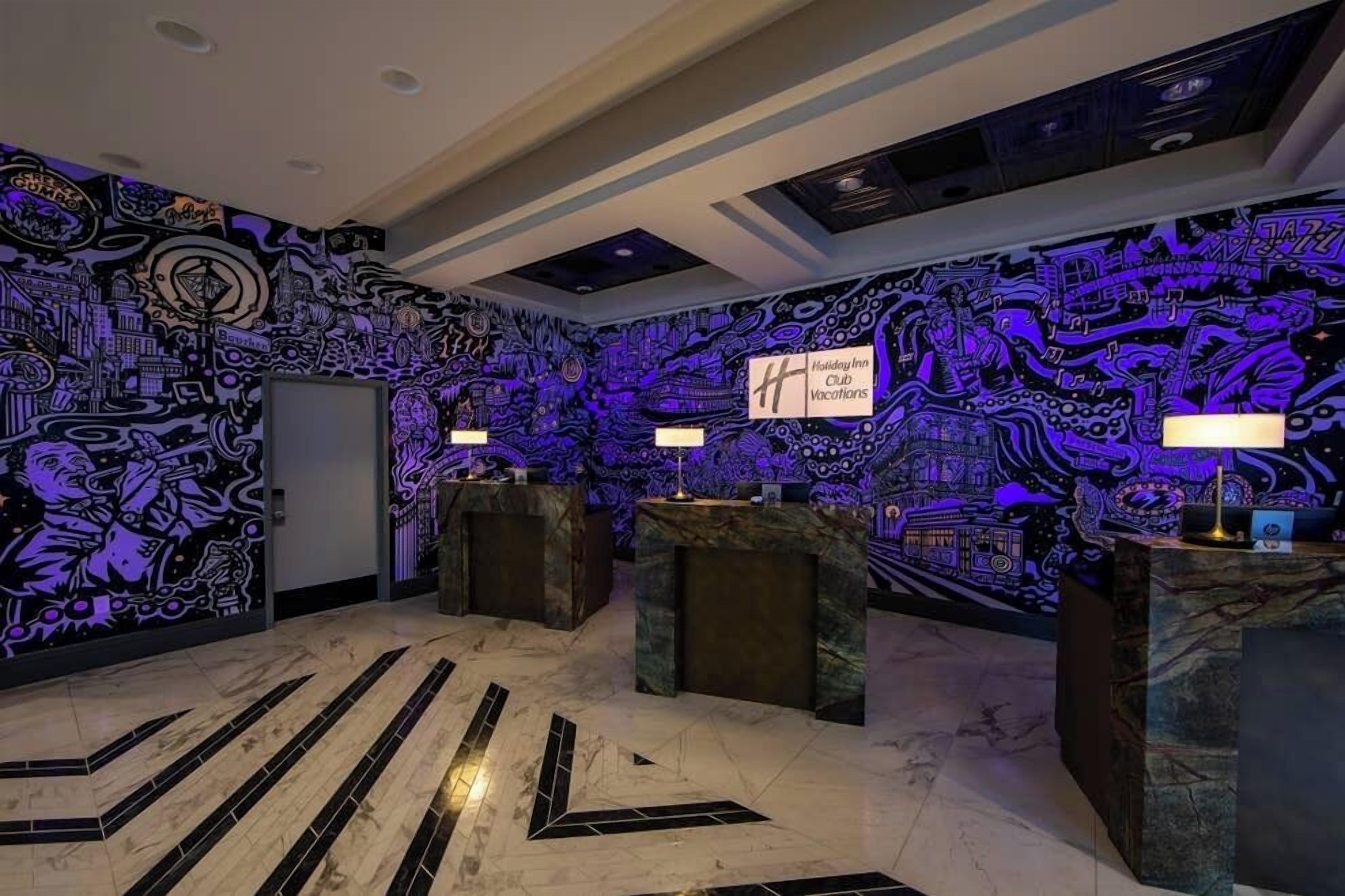 Un vestíbulo con un mural iluminado y llamativo, y una zona de recepción.