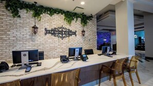 Un comptoir d’accueil équipé d’ordinateurs HP et Dell, d’un téléphone et d’une caisse enregistreuse.