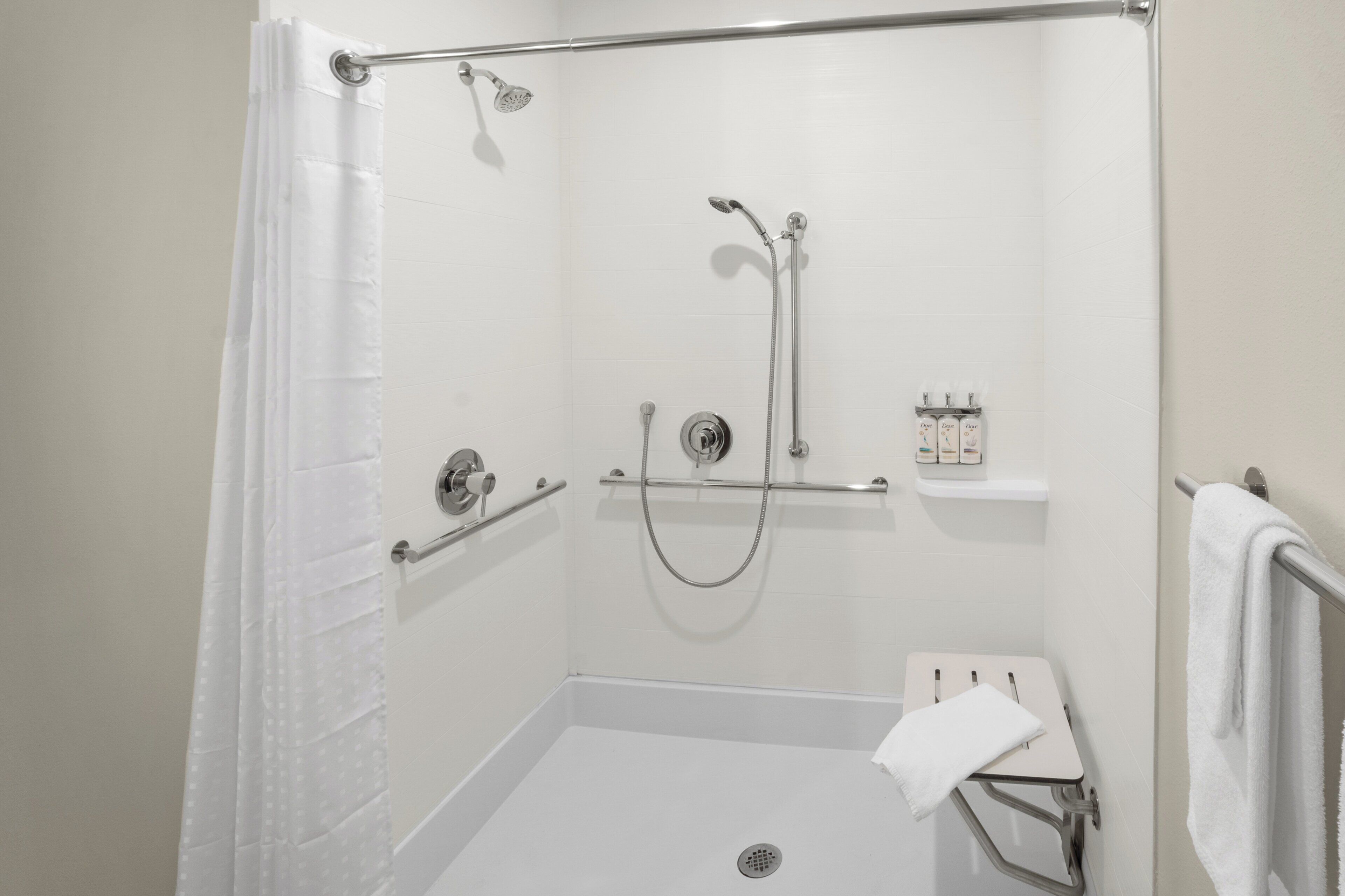 A walk-in shower with a showerhead, handheld shower, and a handheld shower attachment.