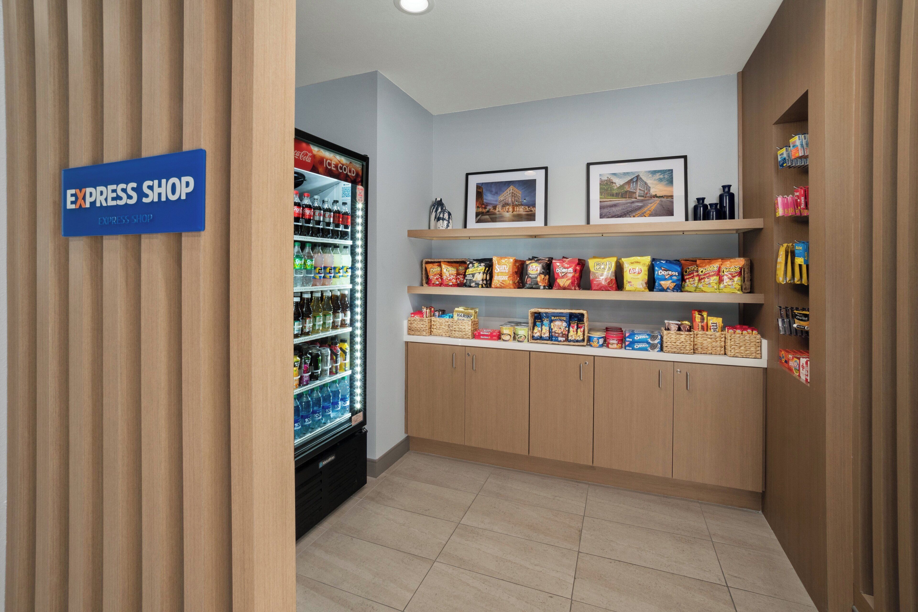 Una tienda de conveniencia limpia y moderna, con una vitrina refrigerada para bebidas y estantes llenos de snacks y refrescos.