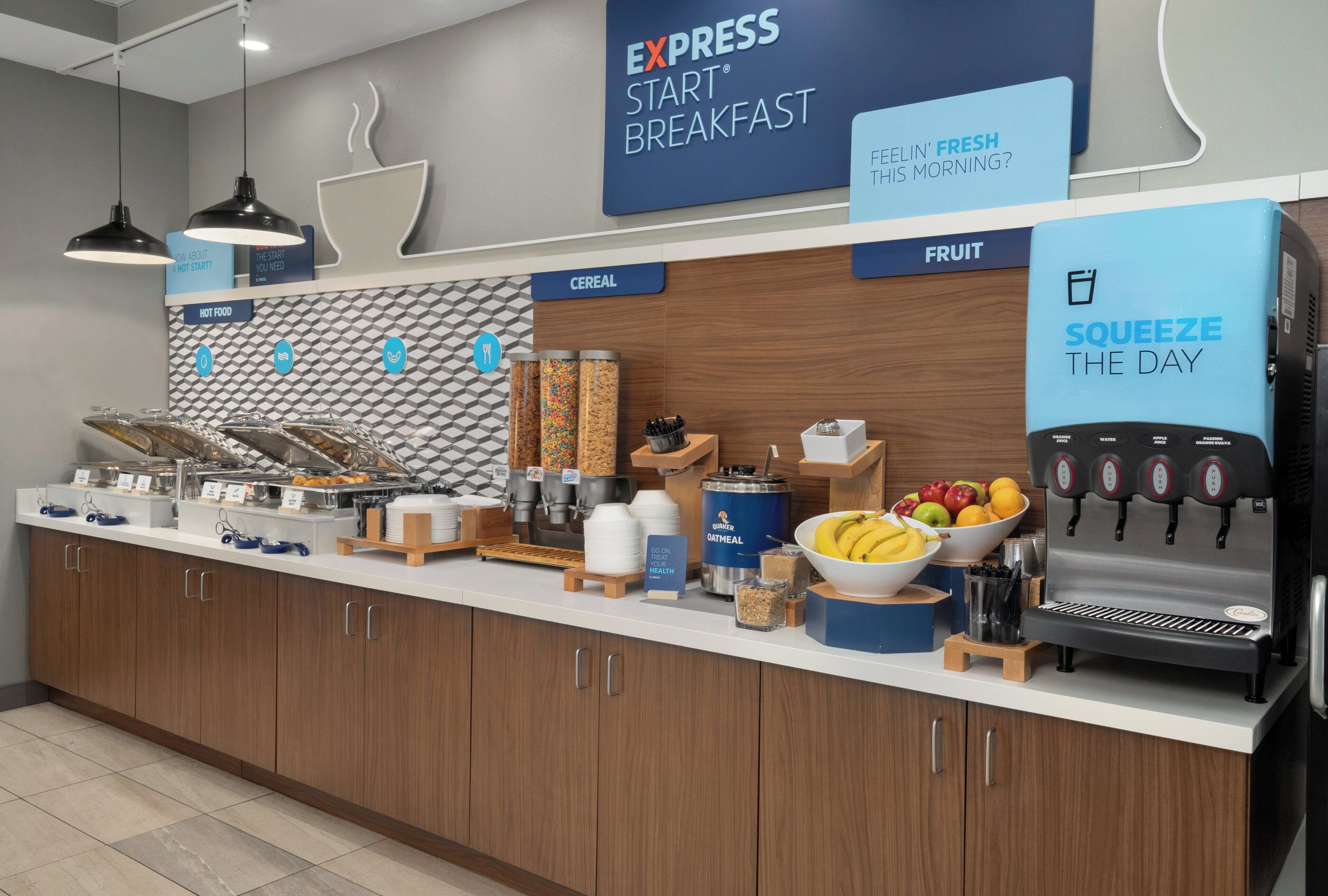 A breakfast bar with labeled sections for cereal, fruit, and hot food, and a beverage dispenser.