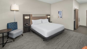 A hotel room with a large bed, a desk, a chair, and a nightstand.