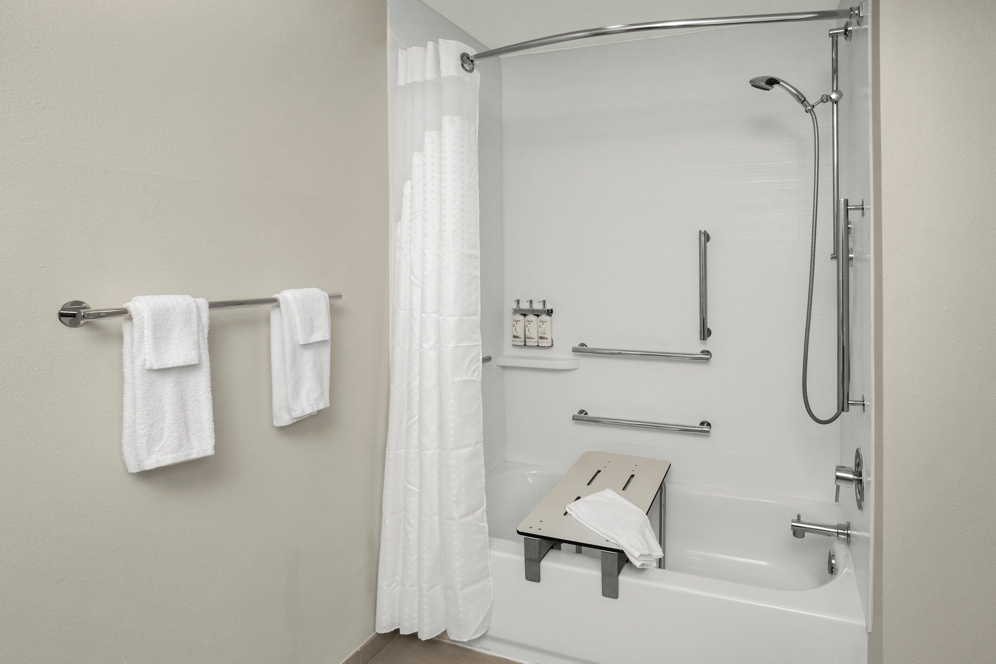 A modern bathroom with a shower, grab bars, and a towel rack.