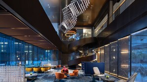 A modern lobby with a curved staircase, seating areas, and large windows. - voco Hefei Binhu by IHG (Hefei)