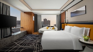 A modern hotel room with a large bed, a flat-screen TV, a view of the city, and a cityscape view from the window. - voco Hefei Binhu by IHG (Hefei)