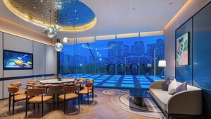 A modern dining area with a large round table, orange chairs, and a city view through large windows. - voco Hefei Binhu by IHG (Hefei)