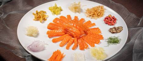 Un plato blanco con varias verduras y hierbas cortadas sobre un paño oscuro.