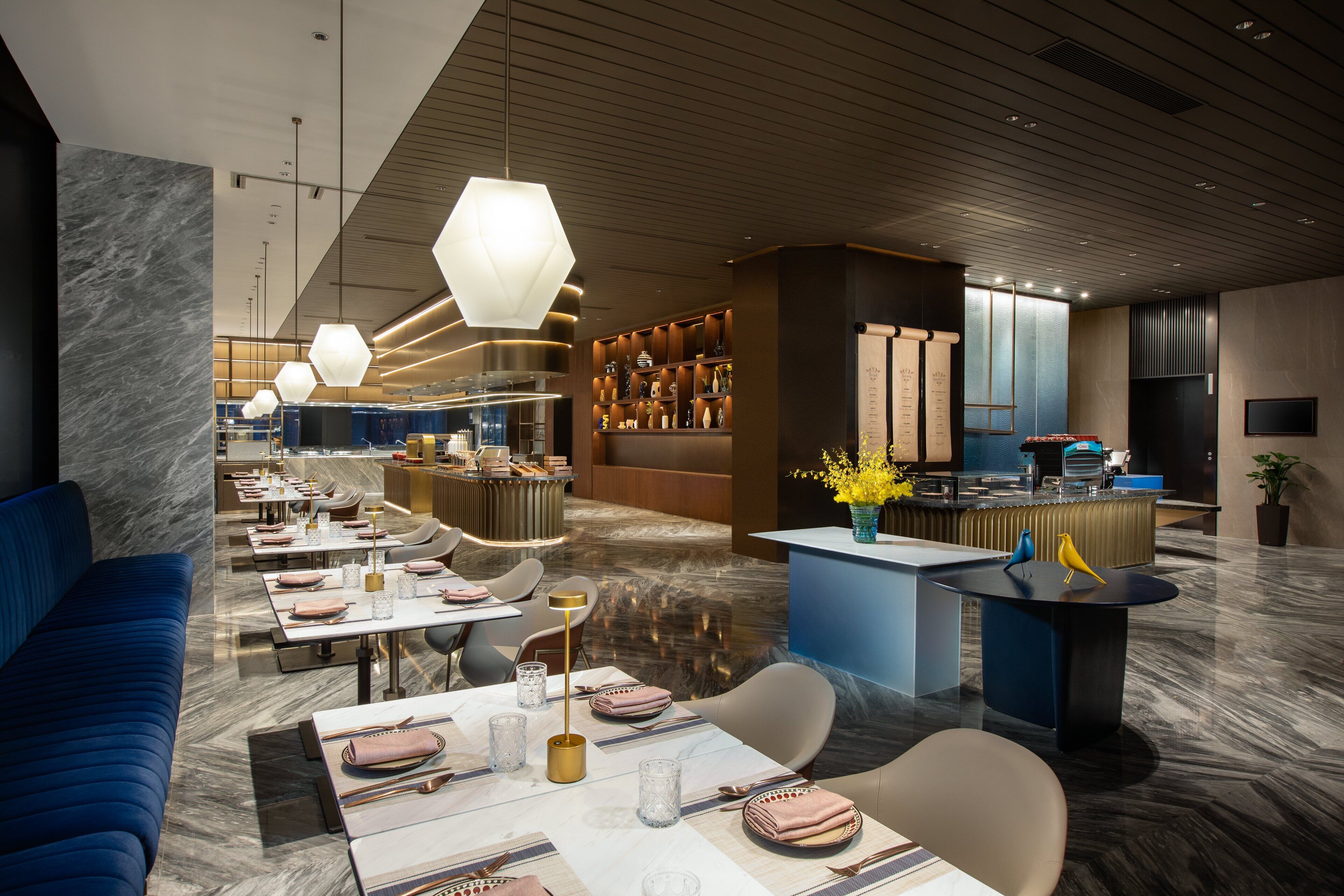 En moderne restaurant med en lang disk, blåt sæde og dekorative fugleskulpturer.