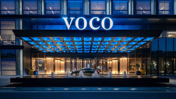 A modern hotel entrance with a glass facade, a car parked in front, and the name "VOCO" illuminated above. - voco Hefei Binhu by IHG (Hefei)