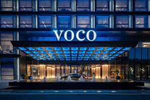 A modern hotel entrance with a glass facade, a car parked in front, and the name "VOCO" illuminated above. - voco Hefei Binhu by IHG (Hefei)
