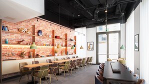 A modern conference room with a brick wall, wooden tables, and chairs. - Staybridge Suites Brighton by IHG (Brighton)