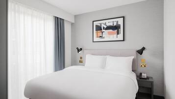 Een moderne hotelkamer met een groot bed, een nachtkastje met een telefoon en een wanddecoratie.
