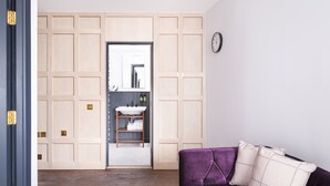 A room with a wooden wardrobe, a purple sofa, and a clock on the wall. - Staybridge Suites Brighton by IHG (Brighton)
