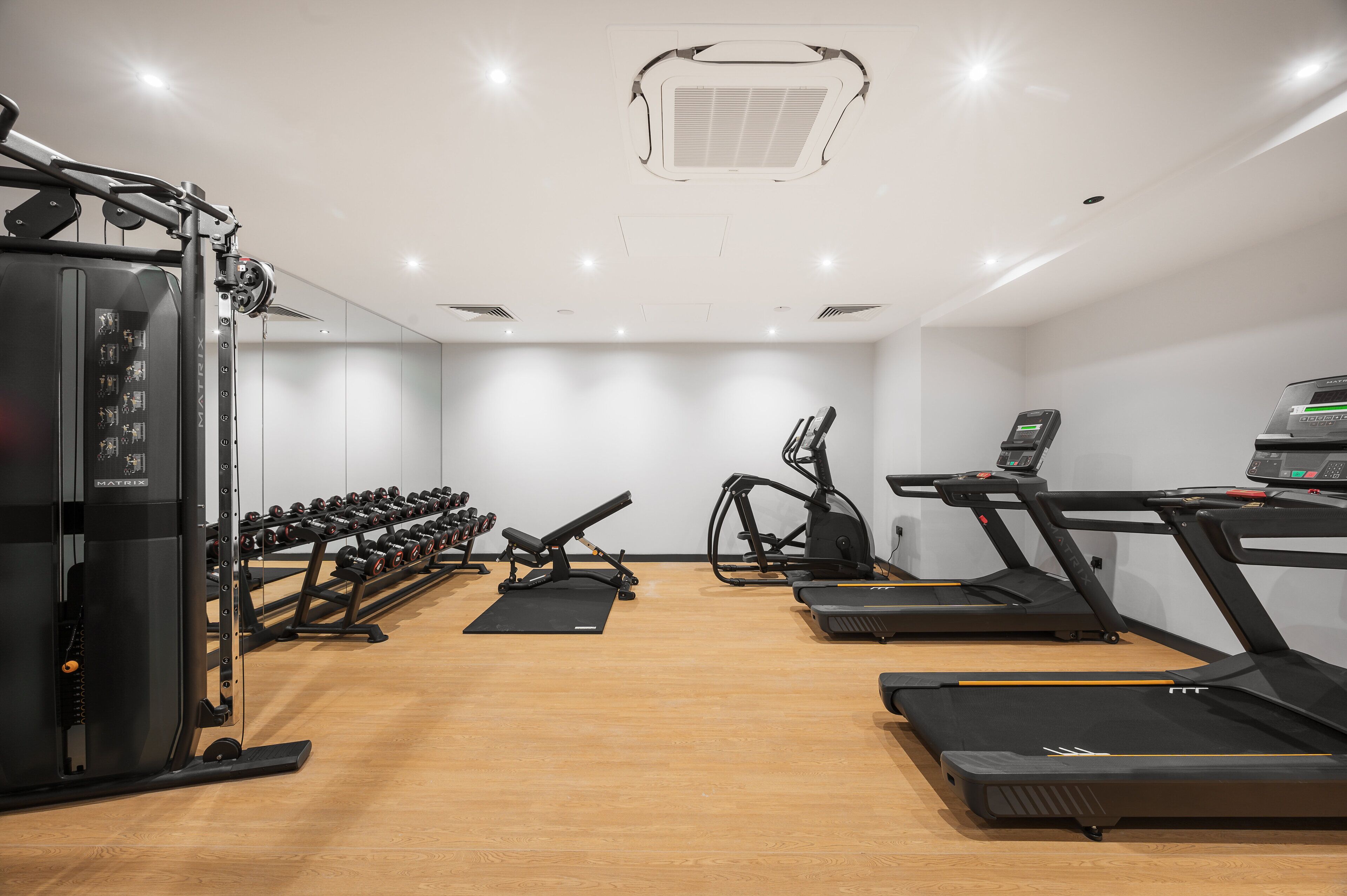 A modern gym with various exercise equipment including treadmills, a stationary bike, and free weights.