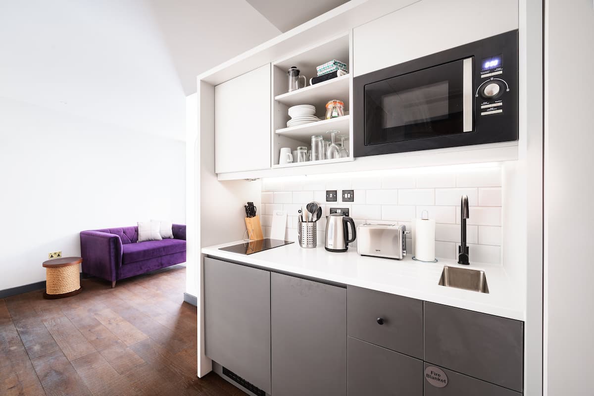 A modern kitchen with white cabinetry, a built-in microwave, a toaster, and a coffee maker.