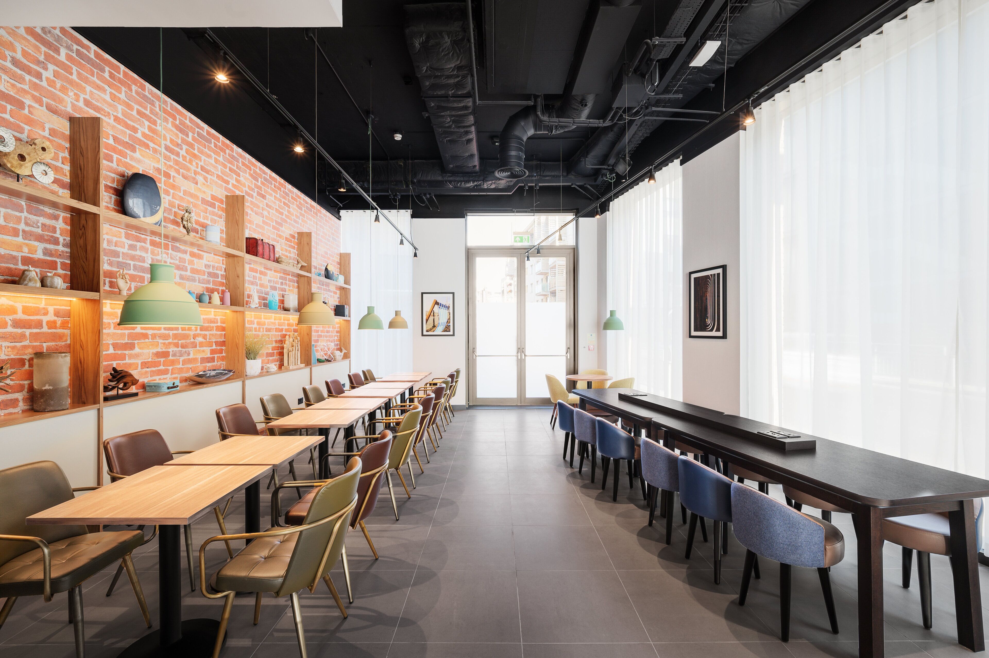 A modern conference room with brick walls, wooden tables, and chairs.