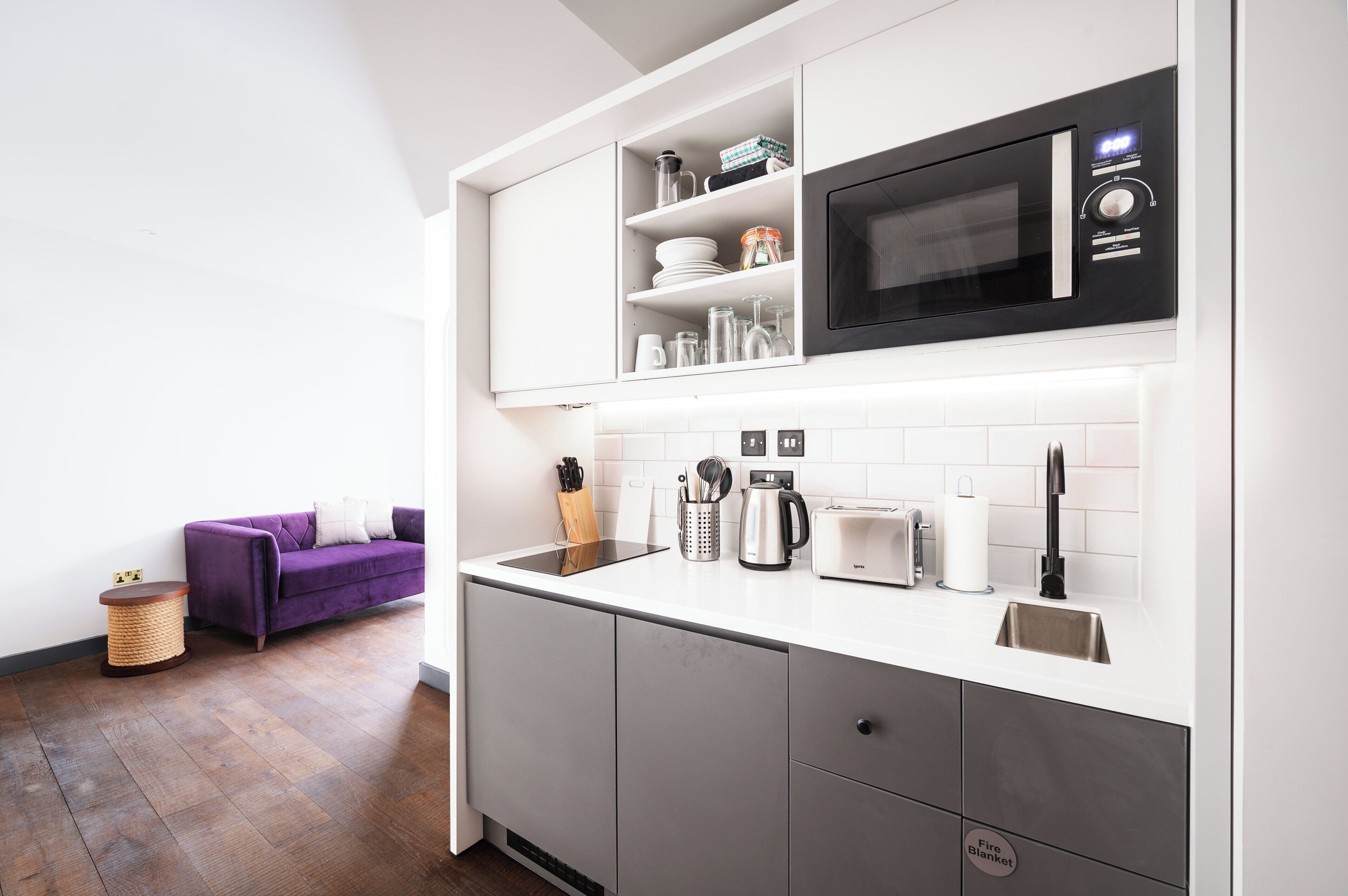 A modern kitchen with a built-in microwave, toaster, and kettle.