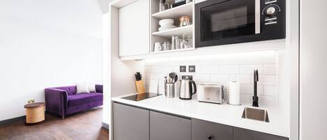 A modern kitchen with a built-in microwave, toaster, and kettle.