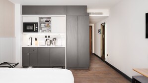 A modern hotel room with a kitchenette, a bed, and a wooden floor. - Staybridge Suites Brighton by IHG (Brighton)
