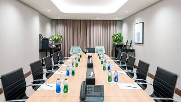 A conference room with a long table, chairs, a phone, and water bottles.